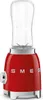 A red SMEG mini-standmixer with a clear blending cup on top, set against a white background. Podgląd zdjęcia produktu