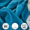 A close-up view of a folded turquoise blanket, with circular icons indicating product features. Produktbild-Vorschau