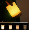 A close-up of a portable LED lamp with a fabric shade and wooden base, shown in a dark setting. Below the lamp, there is a slider indicating brightness control, and four smaller images of the lamp at different brightness levels. Produktbild-Vorschau
