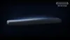 A sleek, black soundbar is presented against a dark, gradient background, with a subtle blue glow emanating from behind it. Anteprima dell’immagine prodotto