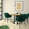 A dining set with four dark green velvet chairs around a round wooden table. Produktbild-Vorschau