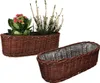 Two oval wicker planters are shown against a white background. One planter is filled with plants, including a flowering plant with pink blooms and a plant with white flowers. The second planter is empty and lined with plastic. Produktbild-Vorschau