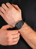 A close-up shot of a person's wrist wearing a black digital watch with a calculator function. Anteprima dell’immagine prodotto