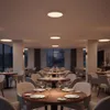 A dimly lit restaurant interior with tables set for dining, illuminated by ceiling lights. Náhľad obrázku produktu