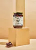 A jar of Kalamata olives is displayed on a light brown cube, with a few olives in a small dish in the foreground. Produktbild-Vorschau