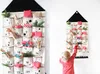 A child reaches for an item in a fabric advent calendar hanging on a wall. Podgląd zdjęcia produktu