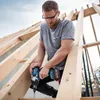 A man is using a cordless impact driver to work on a wooden roof structure. Podgląd zdjęcia produktu