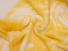 A close-up view of a folded yellow blanket with a white leaf pattern. Náhľad obrázku produktu