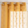 A close-up view of a yellow curtain with a gold leaf pattern, hanging from a white curtain rod. Podgląd zdjęcia produktu