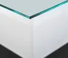 A close-up view of the corner of a glass tabletop on a white surface, with a shadow cast on a black surface below. Voir les images du produit