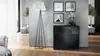 A modern living room with a black sideboard, a floor lamp, and artwork on the wall. Produktbild-Vorschau