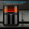 A black air fryer with an orange glow visible through its transparent top sits on a countertop with a blurred kitchen background. Náhľad obrázku produktu