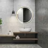 A modern bathroom with a round LED mirror above a sink. Voir les images du produit