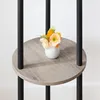 A close-up of a round shelf on a coat rack, holding a small white vase with artificial flowers. Náhled obrázku produktu