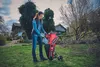 A woman is using a red garden shredder in a backyard with houses and trees in the background. Podgląd zdjęcia produktu