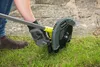 A person is using a Ryobi trimmer to edge a lawn next to a stone pathway. Podgląd zdjęcia produktu