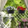 Two black hanging planters filled with colorful flowers are displayed on a white lattice fence on a balcony, with a white table and teacups in the foreground. Produktbild-Vorschau
