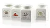 Four white ceramic spice jars with labels and illustrations of spices. Produktbild-Vorschau