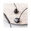 A close-up shot of black earphones on a textured surface. Podgląd zdjęcia produktu