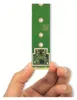 A hand holding a small green circuit board with gold connectors. Podgląd zdjęcia produktu