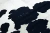 A close-up view of a cowhide rug with black and white patches. Produktbild-Vorschau