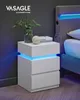 A white nightstand with LED lighting next to a bed. Náhľad obrázku produktu