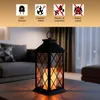 A black lantern with a flickering LED candle inside, placed on a coffee table in a living room setting. Produktbild-Vorschau