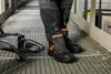 A person wearing work boots and pants stands on a metal grate walkway next to a welding machine. Produktbild-Vorschau