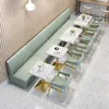 A cafe or restaurant interior with a long green booth seat and several small marble-top tables with gold bases, accompanied by light green chairs. Voir les images du produit