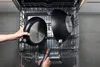 A person is placing pans into a dishwasher. Produktbild-Vorschau