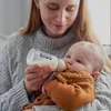 A woman is feeding a baby with a bottle. Voir les images du produit