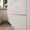 A close-up view of a white wardrobe with subtle detailing and a wooden floor. Produktbild-Vorschau