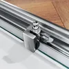 A close-up view of a shower door sliding mechanism, showing the chrome-plated metal components and a section of wooden flooring in the background. Produktbild-Vorschau