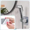 A collage showing a bidet shower head mounted on a wall and a close-up of hands peeling adhesive backing from a mounting bracket. Náhľad obrázku produktu