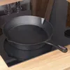A cast iron skillet is placed on a black induction stovetop, with wooden cabinetry in the background. Produktbild-Vorschau