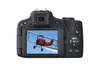 The back of a digital camera displaying an image of a red biplane in flight. Produktbild-Vorschau