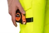 A person's hand holds a tape measure attached to a bright yellow work pant. Produktbild-Vorschau