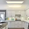 A modern, white kitchen with sleek cabinetry and stainless steel appliances, illuminated by two large, flat LED ceiling panels. Produktbild-Vorschau