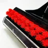 A close-up view of a red brush head on a black cleaning device. Voir les images du produit
