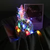 A decorative pineapple object with colorful LED lights wrapped around it, placed on a dark fabric surface next to a framed picture. Produktbild-Vorschau