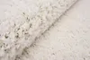 A close-up view of a fluffy, cream-colored rug. Voir les images du produit
