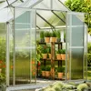 A greenhouse filled with plants, with sliding doors open to the outside. Produktbild-Vorschau