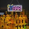 A neon sign that says "BAR" with a cocktail glass is displayed above a shelf filled with bottles of alcohol. Náhľad obrázku produktu