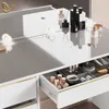 A close-up view of a white vanity table with gold accents, showing an open drawer filled with makeup. Produktbild-Vorschau