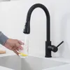 A person is filling a glass with water from a black kitchen faucet. Produktbild-Vorschau