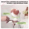 A hand is shown using a pink yarn winder to wind pink yarn. The background includes a wooden box with flowers and a ball of white yarn. Produktbild-Vorschau
