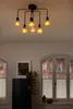 A ceiling light fixture with multiple Edison-style bulbs hangs above a refrigerator and a window in a room. Produktbild-Vorschau