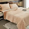 A cozy bedroom scene with a plush blanket draped over a bed, featuring pillows and a bedside table. Produktbild-Vorschau