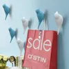 Several bird-shaped wall hooks with a pink shopping bag hanging on two of them. Voir les images du produit