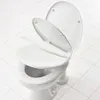 A white toilet with the seat and lid open, shown on a white tiled floor. Produktbild-Vorschau